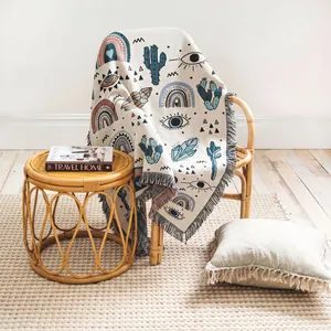 Bohemian woven throw blanket with fringe draped over a rattan chair in a cozy room