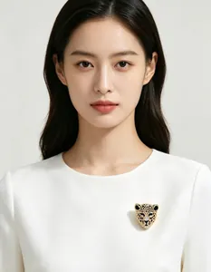 Gros plan d'une luxueuse broche tête de léopard avec strass étincelants sur robe blanche.
