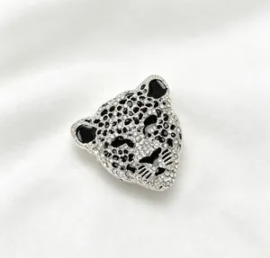 Détail macro d'une broche tête de léopard argentée avec strass scintillants et émail noir.