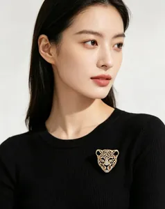 Vue détaillée d'une broche tête de léopard scintillante en strass sur un pull noir élégant.