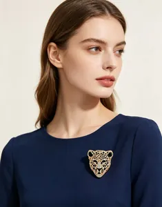 Élégante broche tête de léopard dorée avec strass scintillants sur une robe bleu marine