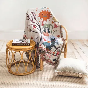 Woven throw blanket with artistic illustration and tassels in a cozy living room