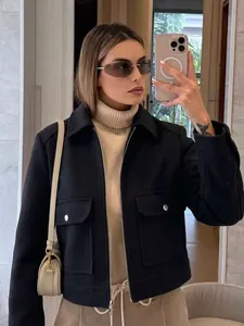 Vrouw draagt een zwart zacht jasje met rits en grote zakken in een spiegel-selfie.