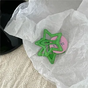 Two green glitter star-shaped hair clips for children on white paper background.