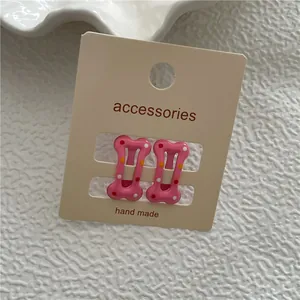 Pinces à cheveux roses en forme d'os pour enfants avec pois colorés sur carte