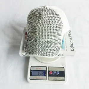 Vista dettagliata di un cappello bianco con strass argentati su una bilancia da 118g