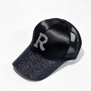 Macro view of rhinestone 'R' letter on a black satin baseball cap with sequin brim