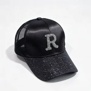 Detailed view of the rhinestone letter R on a black satin and glitter baseball cap