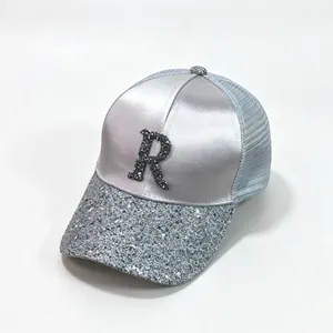 Close-up of sparkling rhinestone R letter and sequin brim on silver satin mesh cap