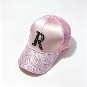 Close-up of pink satin mesh baseball cap with black rhinestone letter R and sequin brim