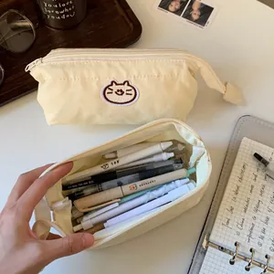 Large capacity cream canvas pencil pouch with cute cat embroidery detail on desk