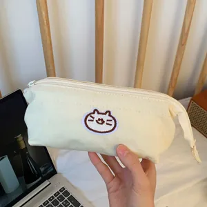 Close-up view of a cream canvas pencil case featuring a cute cat embroidery patch