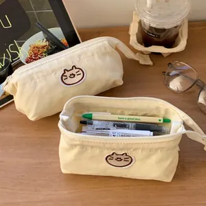 Close-up of a cream canvas pencil case with a cute cat patch showing pen storage