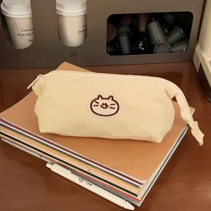 Detail view of a cream canvas pencil case with a cute cat embroidery on books
