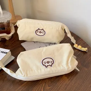 Detail view of two cream canvas pencil pouches featuring cute cat embroidery patches.