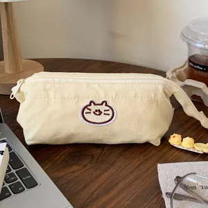 Close-up of cream canvas pencil case with cat embroidery on a wooden study desk