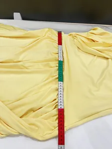 Detailed view of a yellow sleeveless ruched dress with waist measurement tape shown.