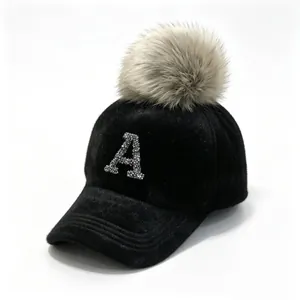 Detail showing a black winter baseball cap with a rhinestone A and a large fur pom-pom