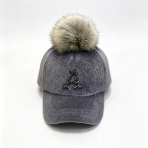 Detail of grey plush baseball cap with rhinestone letter A and faux fur pom-pom.