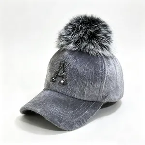 Close-up of a grey fuzzy baseball cap with a fluffy pom-pom and rhinestone letter A
