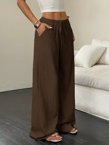 Détail montrant la texture plissée et la taille à cordon de ce pantalon large marron décontracté.