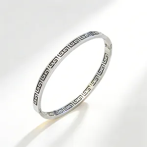 Vista dettagliata del motivo a greca continua sul bracciale rigido in acciaio argento