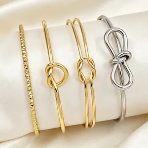 Vista dettagliata di vari bracciali a nodo in acciaio inossidabile color oro e argento.