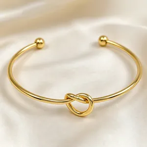 Vista dettagliata dell'elegante nodo dorato su un bracciale rigido dal design minimalista.