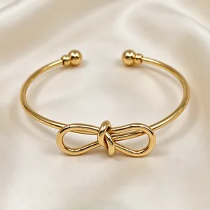 Elegante bracciale rigido in acciaio inossidabile dorato con nodo centrale in dettaglio