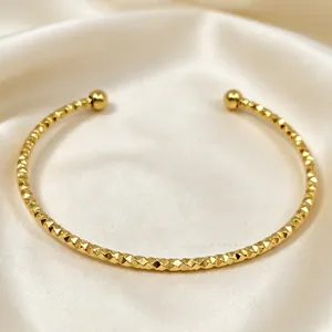 Bracciale rigido in acciaio dorato con texture piramidale su seta bianca lucida.