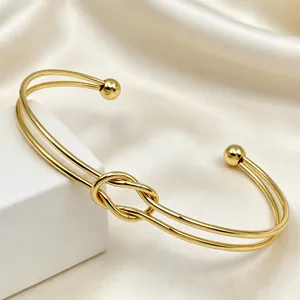 Dettaglio di un elegante bracciale rigido a nodo in acciaio inossidabile dorato su seta