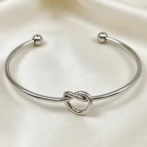 Primo piano del bracciale rigido a nodo in acciaio inossidabile argento su seta lucida