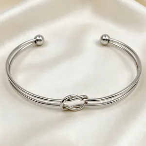 Dettaglio del bracciale rigido a nodo in acciaio inossidabile argento su raso chiaro