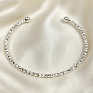 Vista dettagliata della trama a taglio diamante su bracciale rigido in acciaio argento