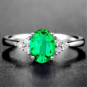 Detaillierte Nahaufnahme eines silbernen Rings mit ovalem grünem Edelstein und Akzentdiamanten.