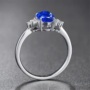 Seitenansicht eines silbernen Rings mit ovalem blauem Saphir und Diamantakzenten