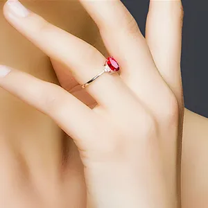 Detailansicht eines eleganten ovalen taubenblutroten Rubinrings an einem Finger