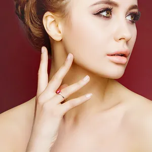 Elegante ovale Ring mit taubenblutrotem Edelstein an dem Finger einer Frau Nahaufnahme.