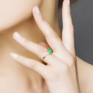 Detailansicht eines eleganten Rings mit ovalem smaragdgrünem Stein am Finger