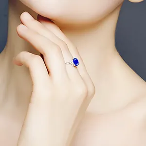 Eleganter blauer Saphirring in Ovalform mit funkelnden Diamanten an einem Frauenfinger