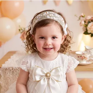 Detailed view of baby girl wearing white lace floral headband with side bows.