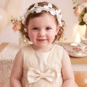 Detail showing a cute toddler girl wearing a white floral lace headband with bows.