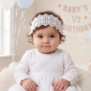 Detail shot of a baby girl wearing a white hollow floral lace headband with side bows