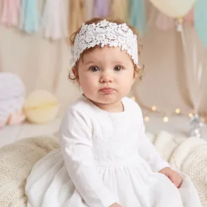 Close-up of white floral lace headband with side bow on a lovely baby girl portrait.
