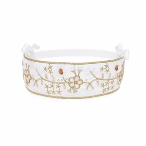 Detailed view of children's white lace headband with gold floral embroidery and sequin accents
