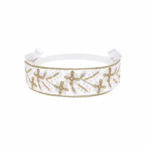 Detail view of a white lace kids' headband featuring gold flower embroidery and bows
