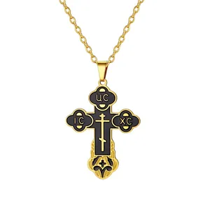 Close-up of golden Orthodox cross pendant with black enamel and traditional symbols