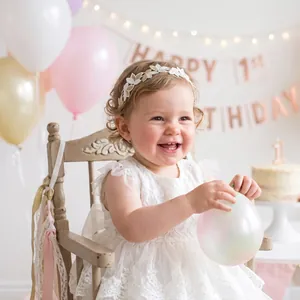 Vue détaillée d'un bébé portant un élégant bandeau floral en dentelle brodée blanche.