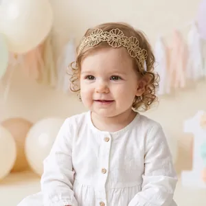 Bébé fille portant un bandeau de fleurs brodées en dentelle dorée dans un décor festif