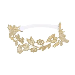 Détail d'un délicat bandeau bébé brodé de fleurs en dentelle dorée avec élastique blanc.